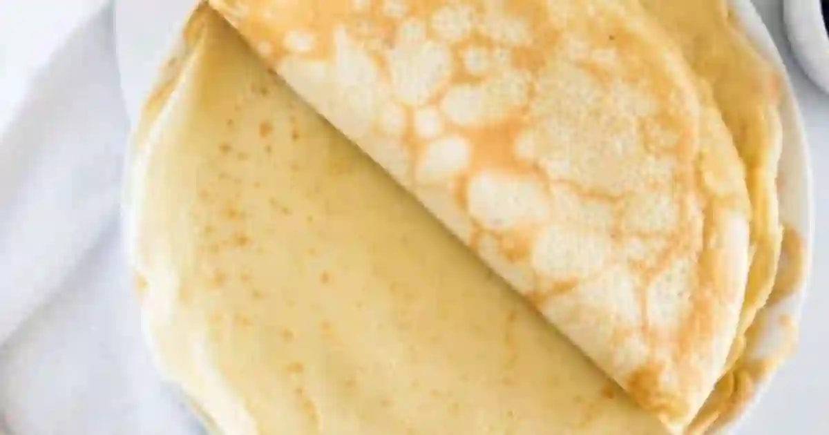 A stack of thin, golden crepes with one crepe partially folded over on top.