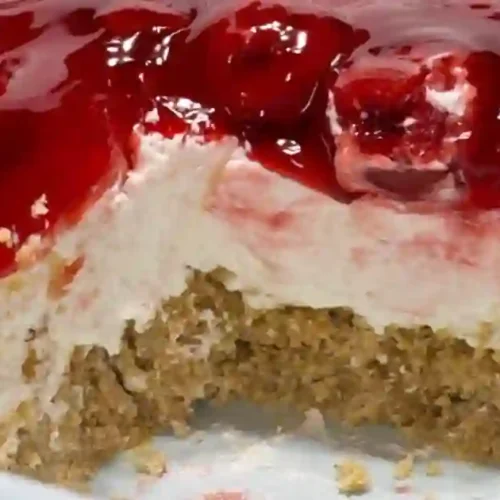 A close-up of a cheesecake topped with cherry glaze, showing a slice removed.