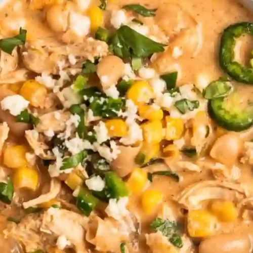 A warm bowl of creamy white chicken chili garnished with fresh cilantro and lime wedges.