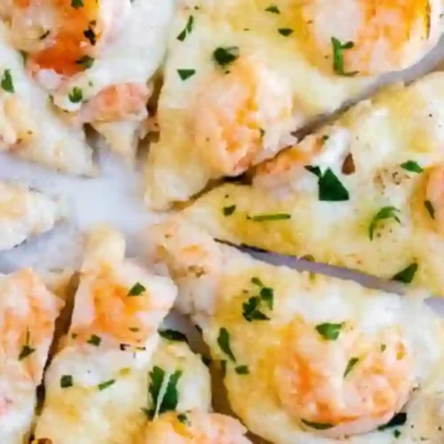 Slices of garlic shrimp pizza topped with shrimp and fresh parsley arranged on a white plate.