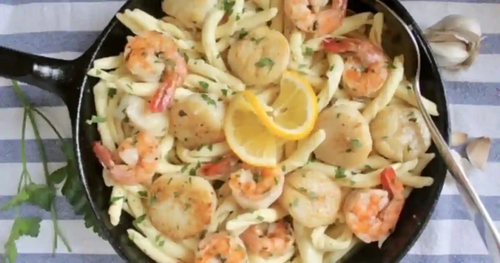 Creamy Seafood Pasta featuring Shrimp and Scallops in Garlic Butter sauce, topped with fresh parsley and lemon slices.