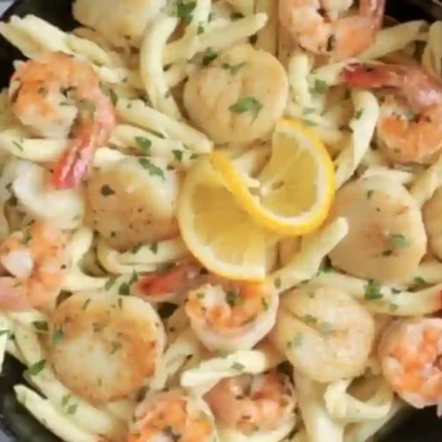 Creamy Seafood Pasta featuring Shrimp and Scallops in Garlic Butter sauce, topped with fresh parsley and lemon slices.