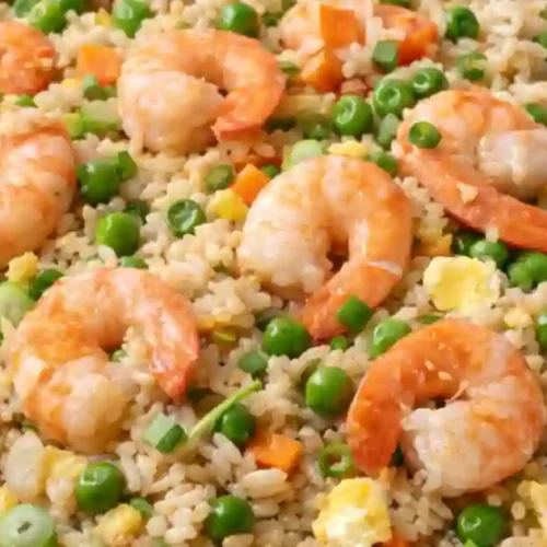 "A close-up of shrimp fried rice, featuring succulent shrimp, peas, carrots, and scrambled eggs in a large serving bowl.