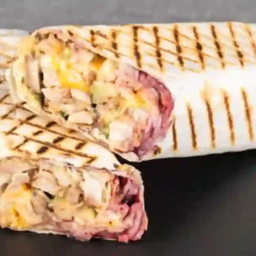 Two grilled BLT wraps, cut in half, showcasing crispy bacon, lettuce, and tomato filling.