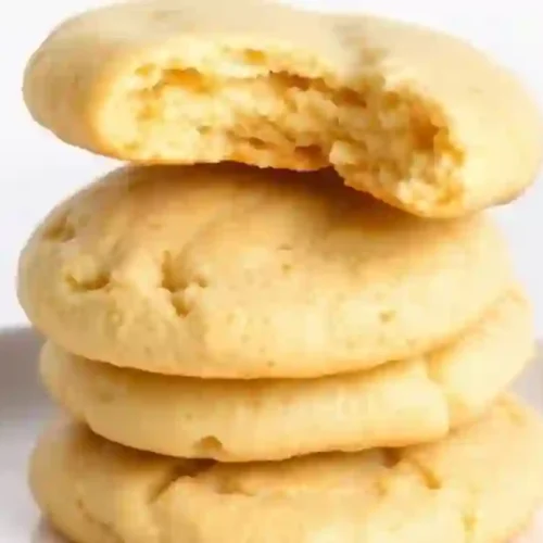 Three stacked Melt in Your Mouth Shortbread cookies, one with a bite taken out of it, on a white plate.