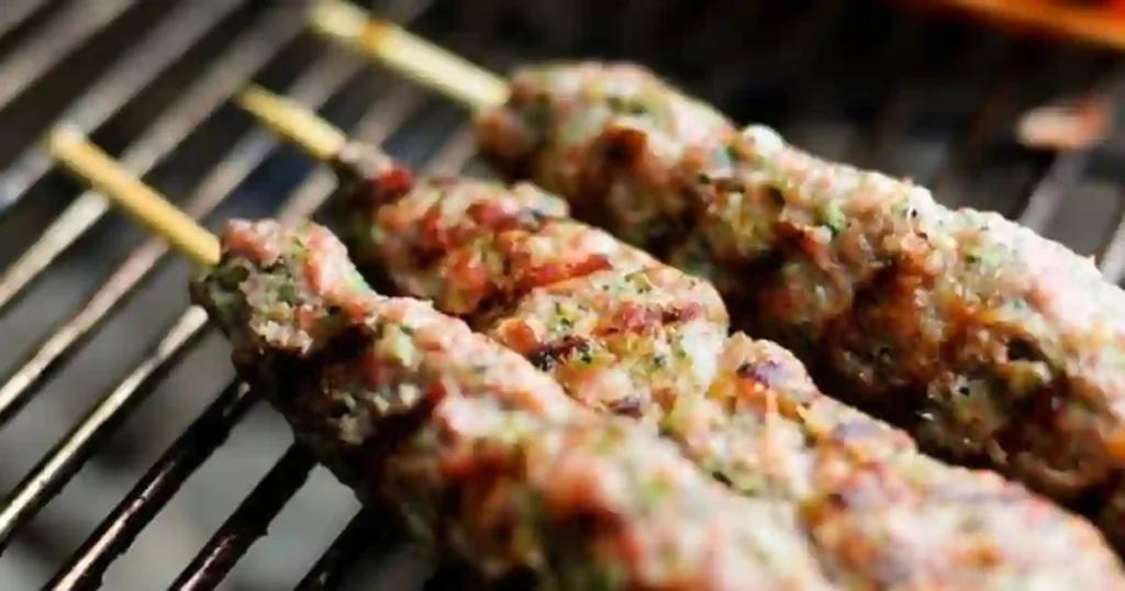 Grilled Lebanese kafta skewers sizzling on a grill, showcasing juicy meat mixed with herbs and spices.